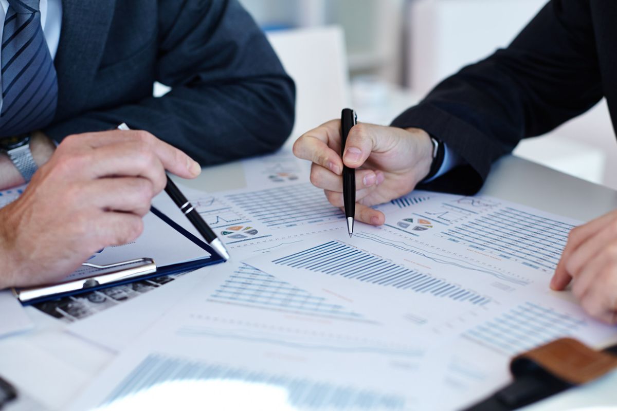 Dos personas revisando gráficas financieras sobre una mesa